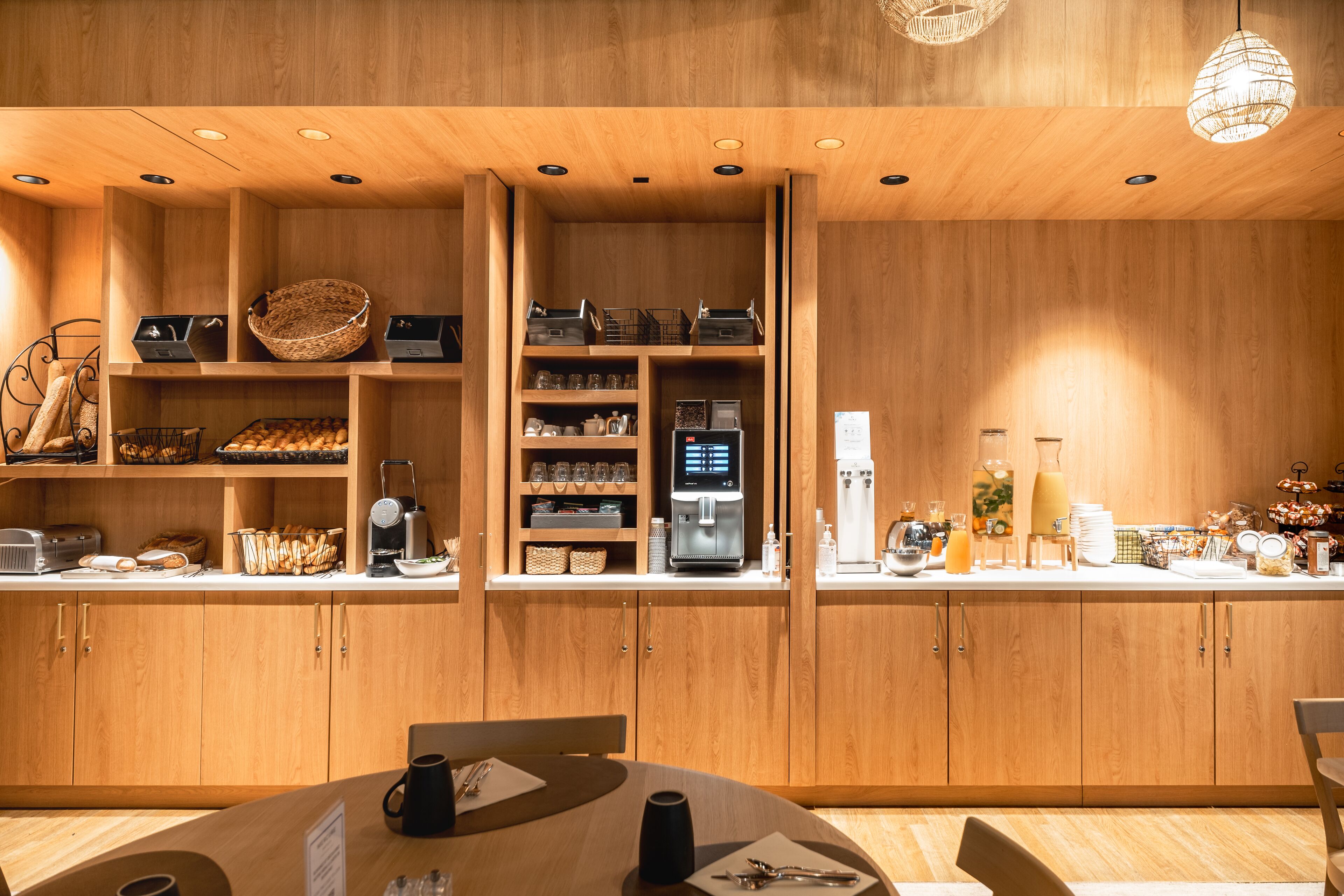 A modern kitchen with wooden cabinetry, a coffee machine, and various kitchen appliances.