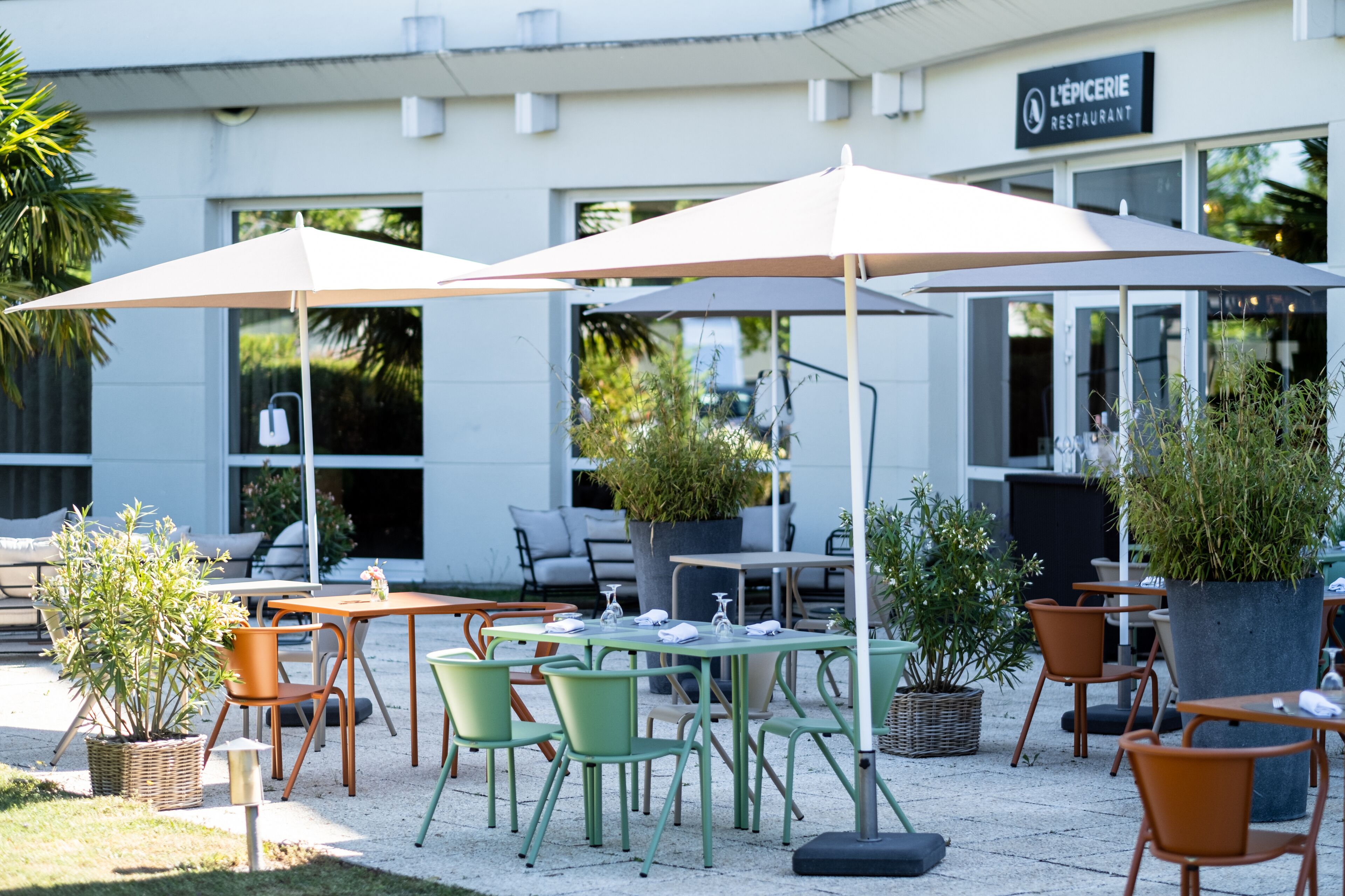 Een terras met tafels, stoelen, parasols en plantenpotten.