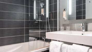 A modern bathroom with a glass-enclosed shower, a white bathtub, and a large mirror above the sink.