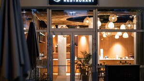 The exterior of L'Epicerie Restaurant with a modern design, featuring large glass doors, a sign above the entrance, and hanging pendant lights visible through the glass. - Mercure Compiegne Sud (Lacroix-Saint-Ouen)