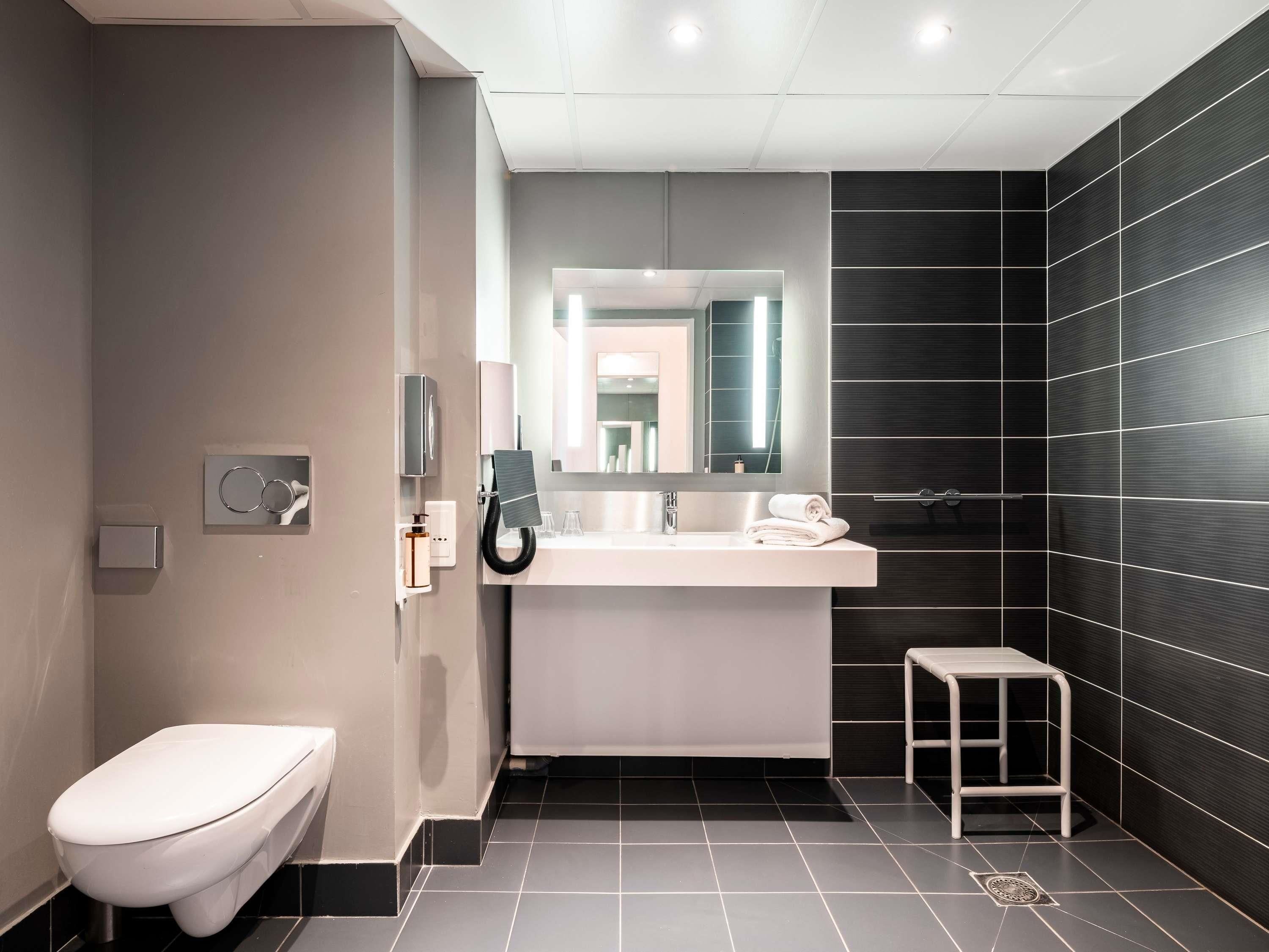 A modern bathroom with a toilet, sink, and mirror.