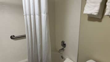 Ein Badezimmer mit einer Badewanne, einer Duschvorhang, einem Handtuchhalter mit Handtüchern und einer Toilette.