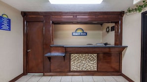 A reception area with a wooden counter, a Days Inn sign, a reception desk, and a tiled floor. - Days Inn by Wyndham El Reno (El Reno)