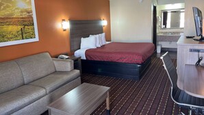 A hotel room with a bed, a sofa, a desk, and a bathroom visible through an open door. - Days Inn by Wyndham El Reno (El Reno)