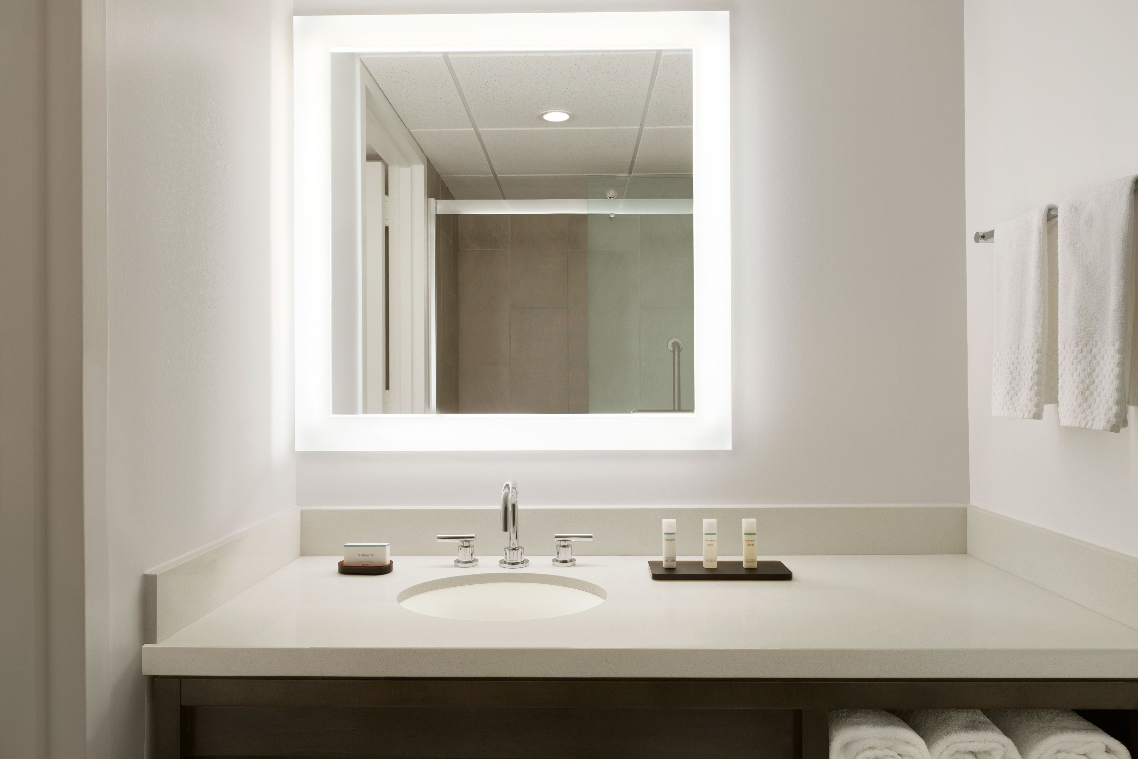 A modern bathroom with a large mirror, a sink, and a shower.