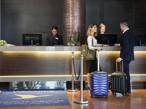 A hotel reception area with a check-in counter, a 'Welcome' mat, and a 'Priority Check-In' sign. - Novotel Sydney Parramatta (Parramatta)