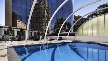 Una piscina al aire libre, sillones reclinables de piscina
