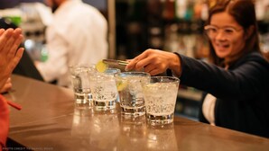 Un bar amb diversos gots d'una beguda transparent, gel i unes rodanxes de llima.