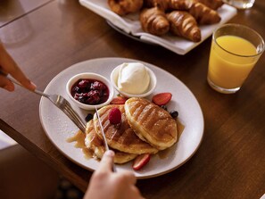A breakfast plate with pancakes, berries, and a glass of orange juice. - Novotel Sydney Parramatta (Parramatta)