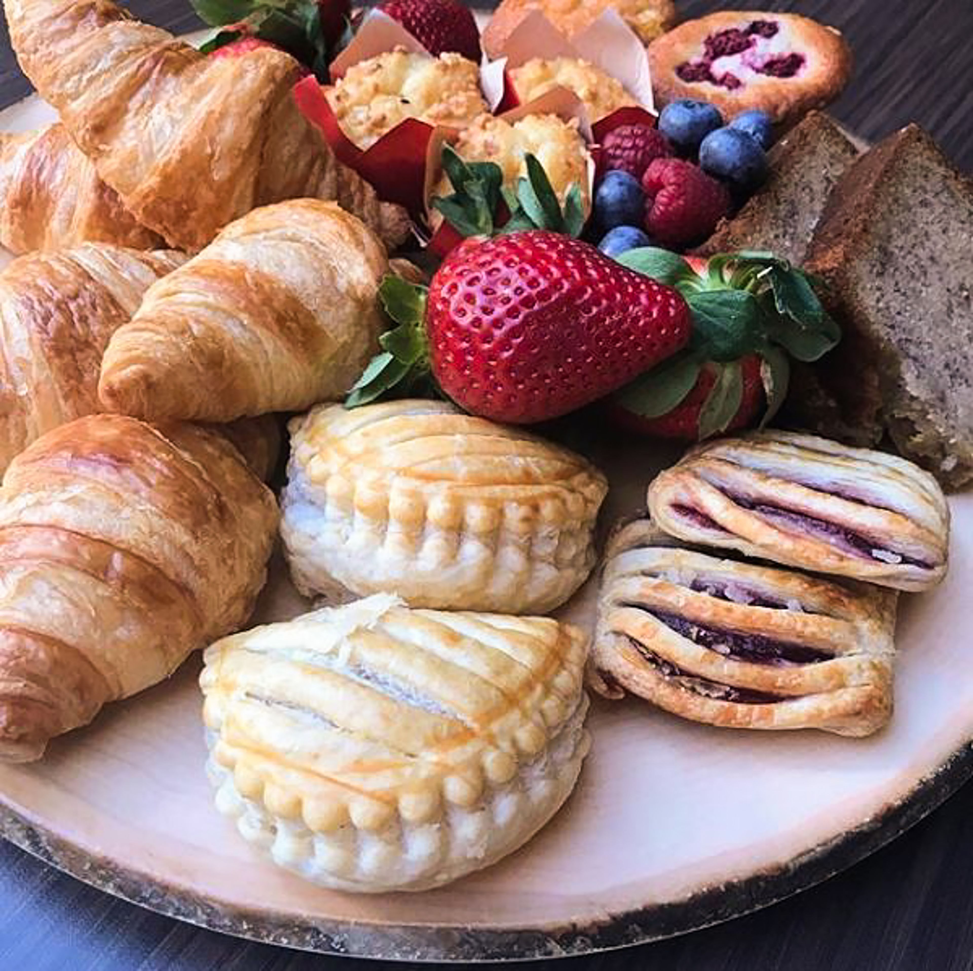 A plate of assorted pastries including croissants, puff pastries, and fruit tarts.