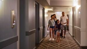 Un passadís d'hotel amb una catifes estampada, una barana a l'esquerra i una porta amb manilla a la dreta.