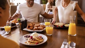Eixam matinal amb croissants, creps i suc d'aranja sobre una taula de fusta.