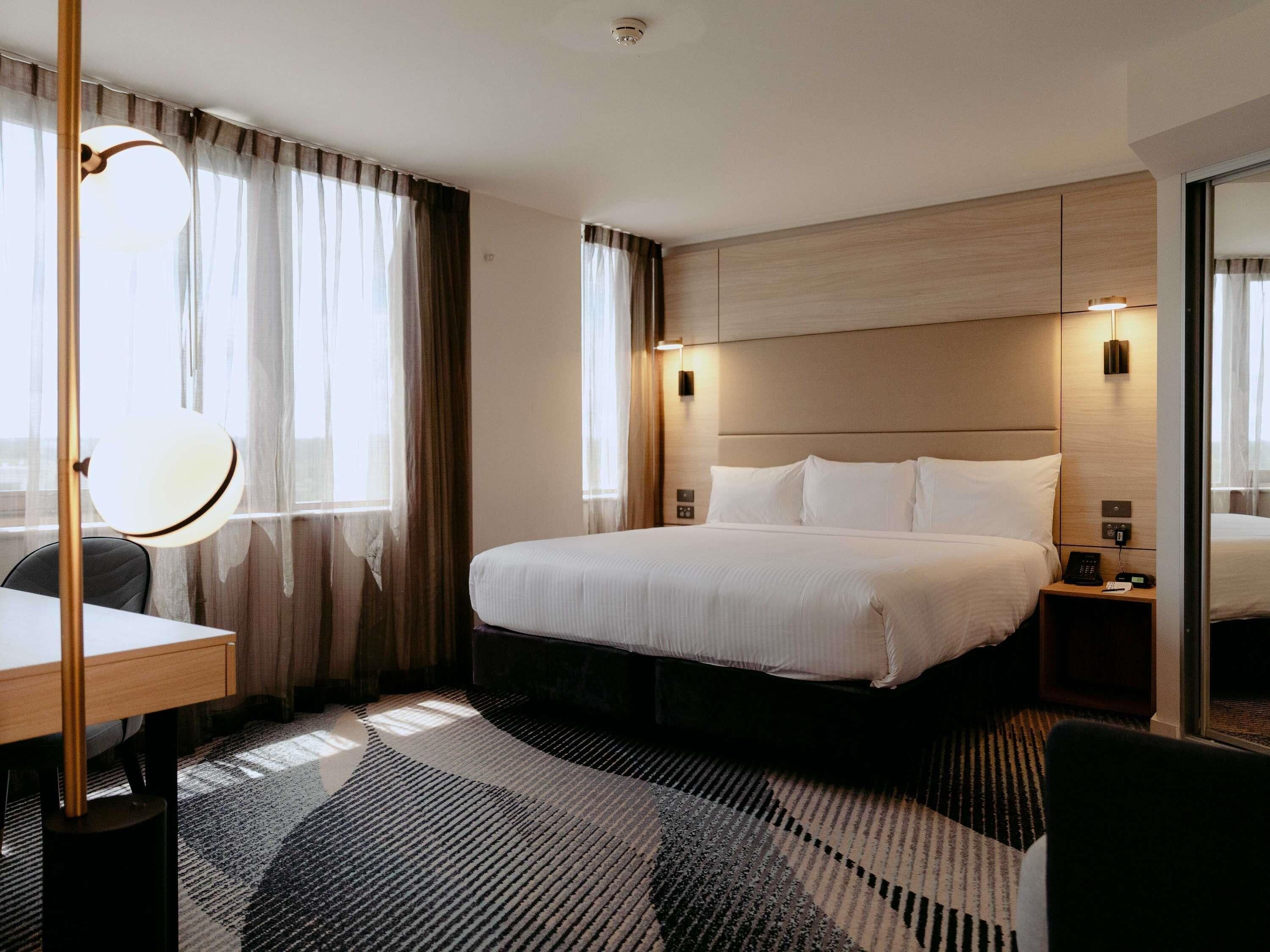 Une chambre d’hôtel avec un grand lit, des tables de chevet, un bureau et une chaise.