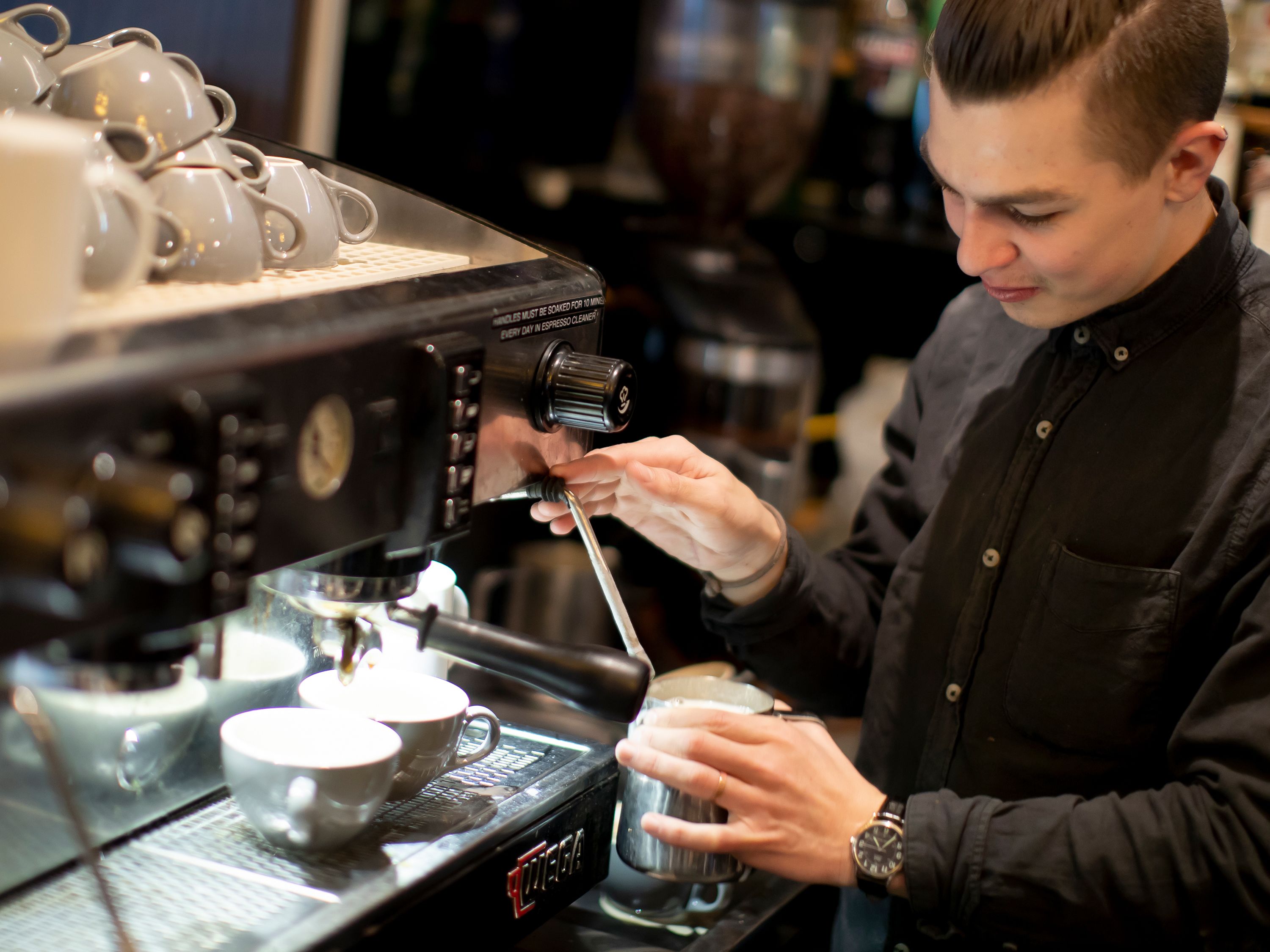 A person operating a coffee machine, preparing a drink.