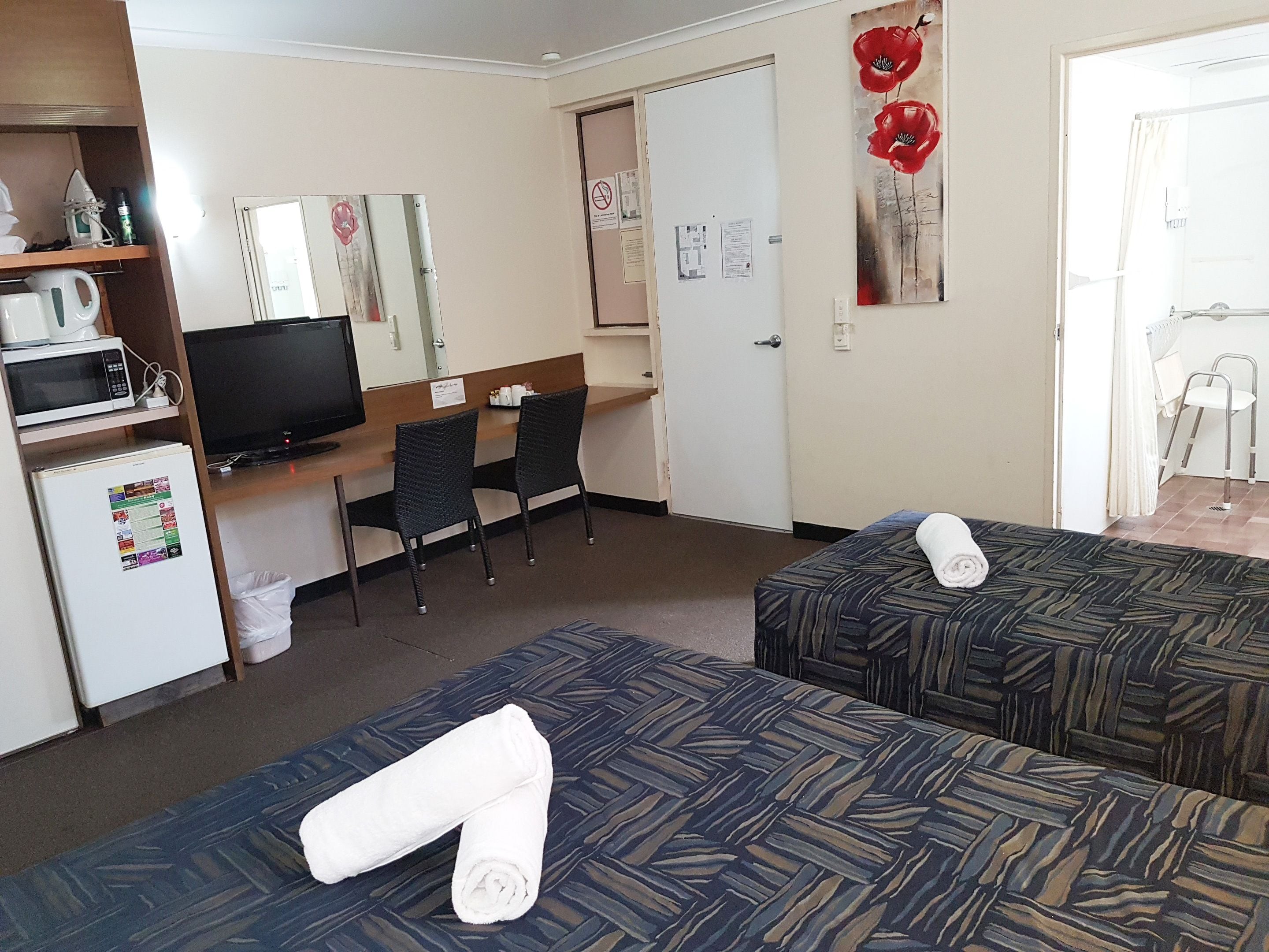 Une chambre d’hôtel avec deux lits, un bureau avec un ordinateur, une télévision et un four à micro-ondes.
