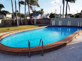 Una piscina al aire libre, sillones reclinables de piscina