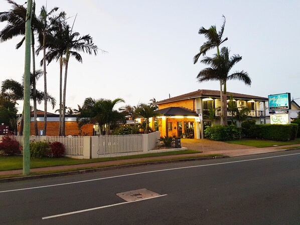 A hotel with a brick facade, a gated entrance, and a signboard advertising a motor inn.