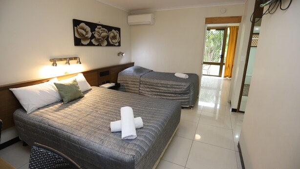 Habitación de hotel con dos camas, zona de estar, un cuadro en la pared y un equipo de aire acondicionado.