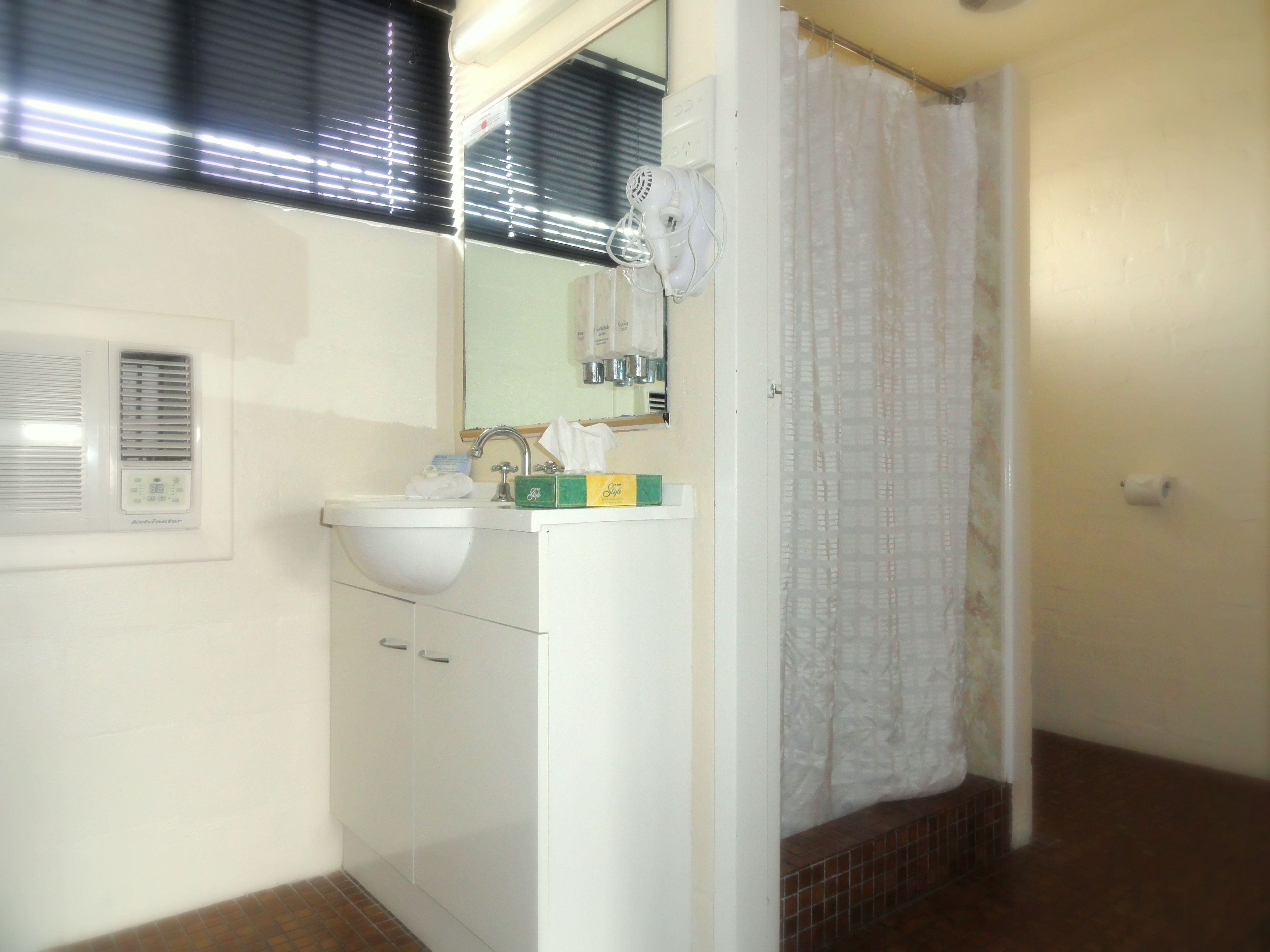 Un baño con lavamanos, espejo y cortina de ducha.