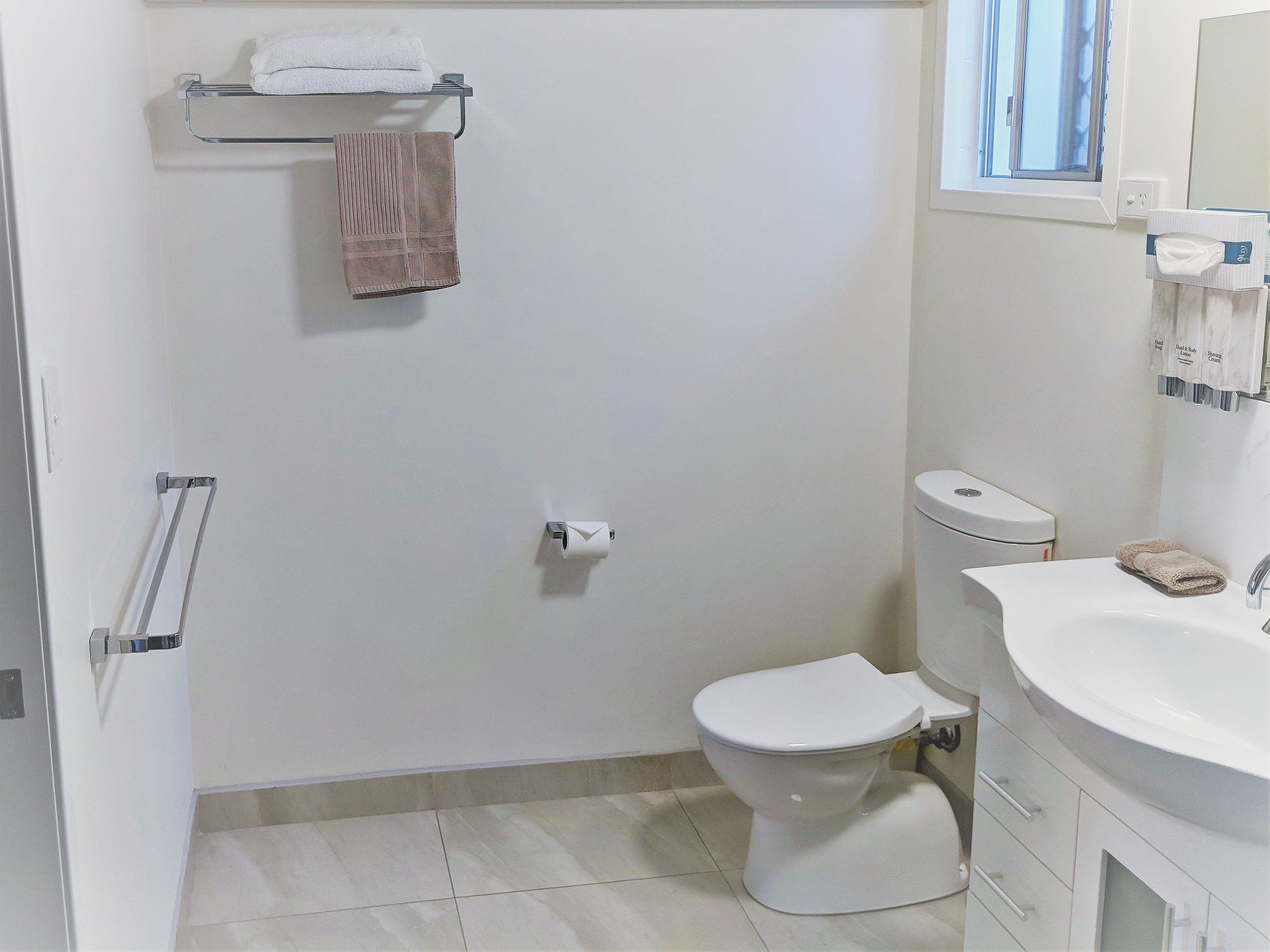 A bathroom with a toilet, sink, and towel rack.