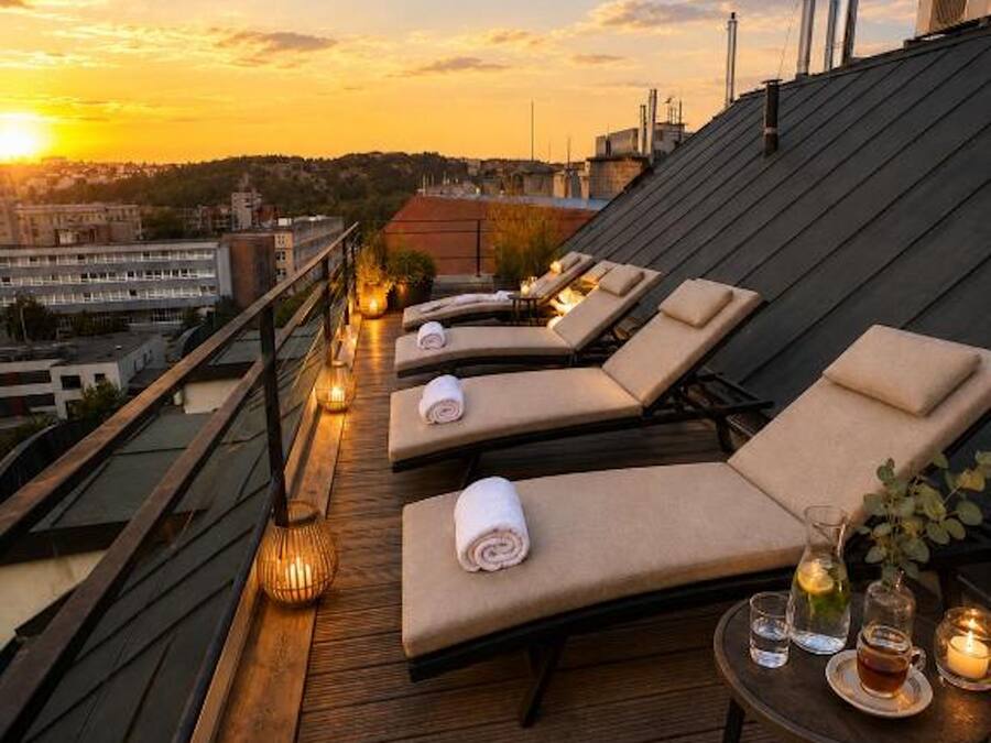 Una terraza en la azotea con sillones, una cubierta de madera y vistas al atardecer.