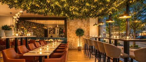 An indoor dining area with a long table, multiple chairs, and hanging lights.
