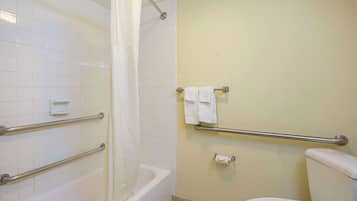 A bathroom with white tiles, a bathtub, a toilet, and a shower curtain.