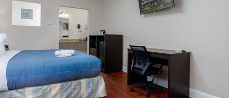 A bedroom with a bed, a desk, and a chair.
