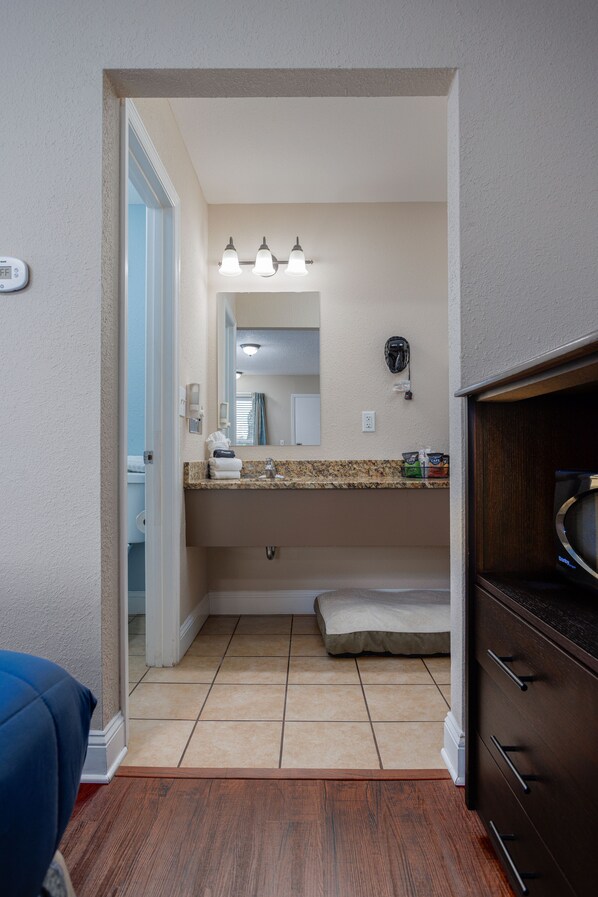 A bathroom with a sink, mirror, vanity, and a shower area. - Quality Inn St Augustine Historic District Area (St. Augustine)