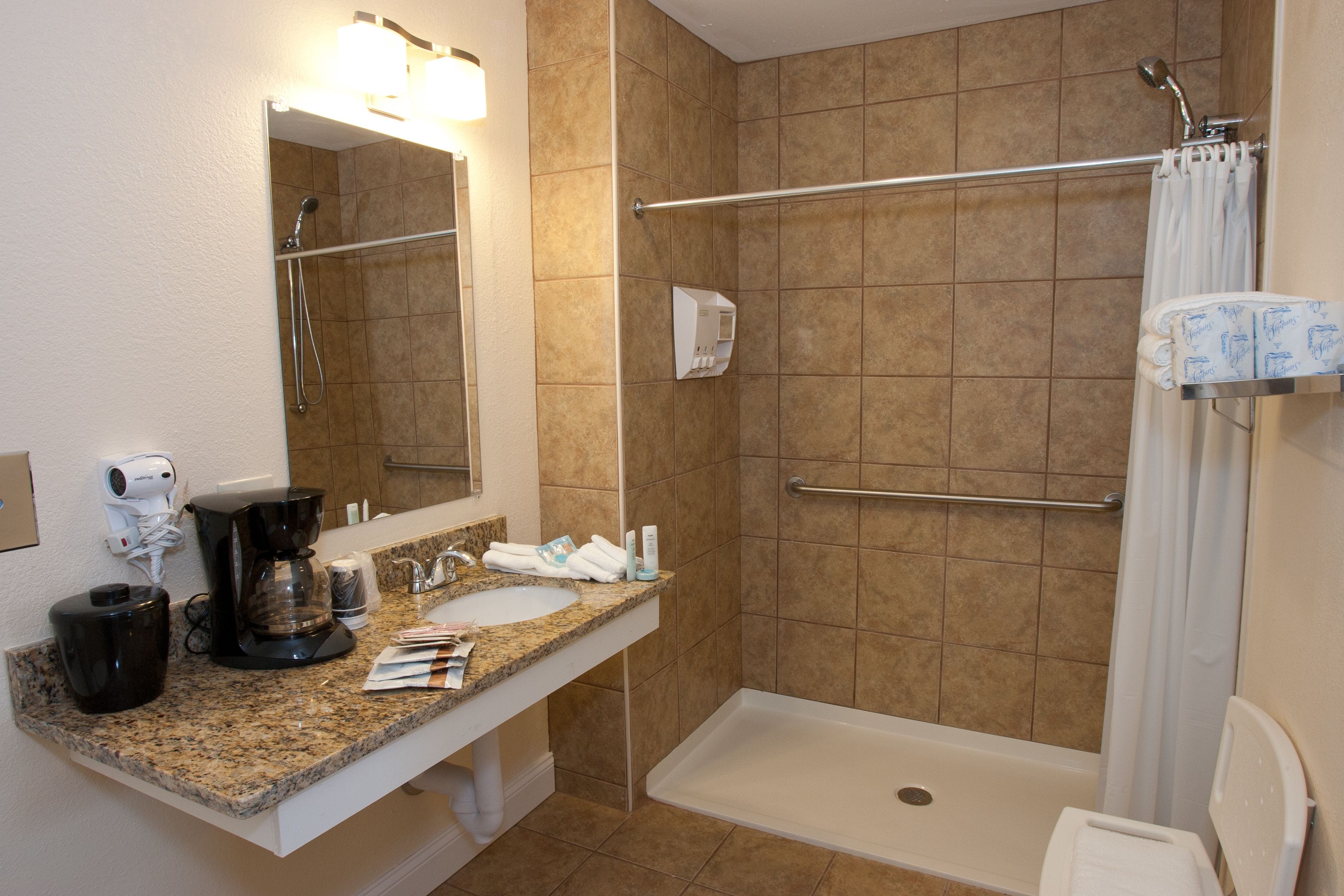 A bathroom with a shower, a sink, a mirror, and a towel rack.