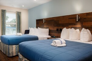A hotel room with two beds, a wooden headboard, and a view of the outdoors.