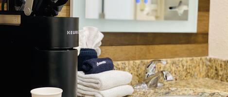 A bathroom with a coffee maker, a sink, and towels.