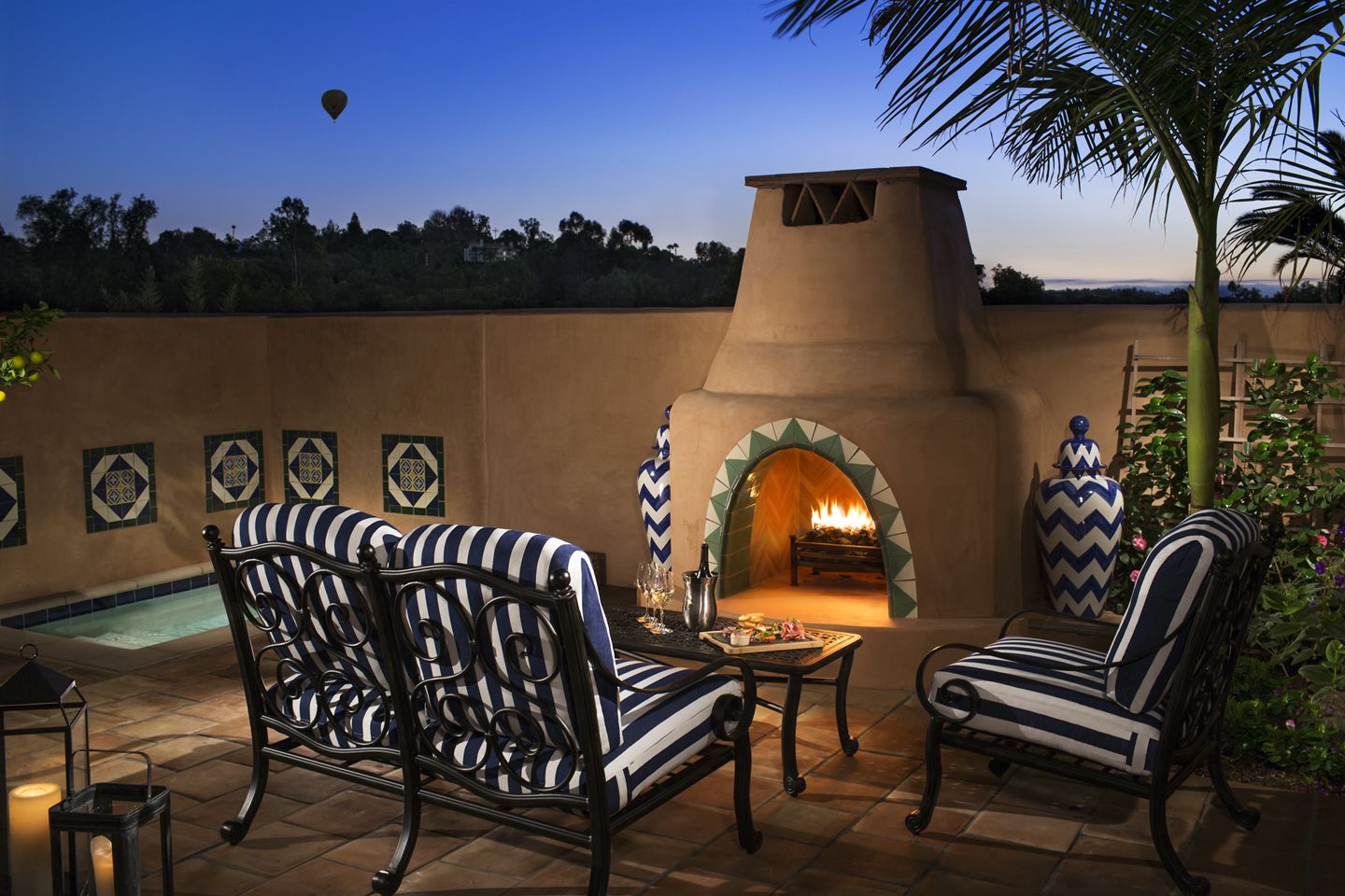 An outdoor seating area with striped chairs and a stone fireplace.