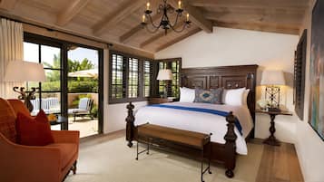 Un dormitorio amplio con una cama grande, un banco, una silla y vistas al exterior a través de amplias ventanas.