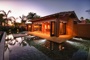 A modern resort with a swimming pool, a covered outdoor area, and a sunset view.