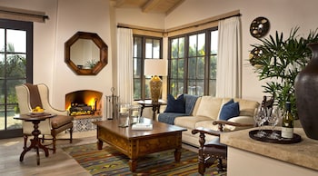 A bathroom with a freestanding bathtub, a double vanity with a mirror, and a window with shutters. at Rancho Valencia Resort and Spa