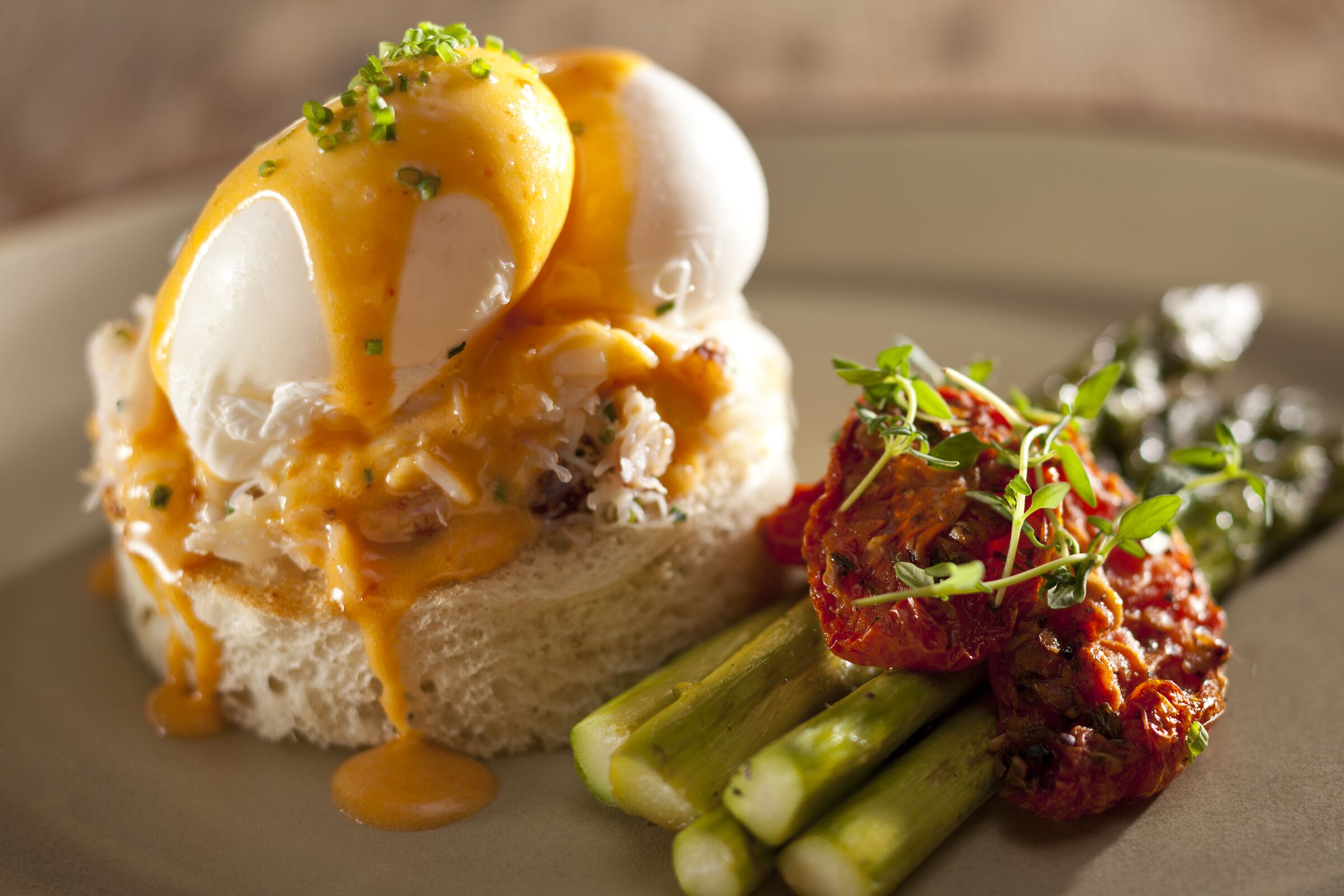 A dish with poached eggs, hollandaise sauce, and asparagus.