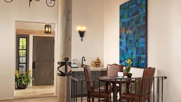 Un comedor con una mesa, sillas, una araña y un cuadro abstracto grande en la pared.