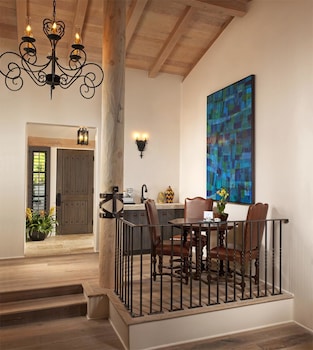 A spacious dining area with a long table set for multiple guests, a fireplace, and a view of the outdoors. at Rancho Valencia Resort and Spa