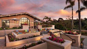 A patio with outdoor seating, a fire pit, and a view of the surrounding landscape. - Rancho Valencia Resort and Spa (Rancho Santa Fe)