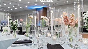 A table set with clear glassware, white flowers, and candles. - Hilton College Station & Conference Center (College Station)