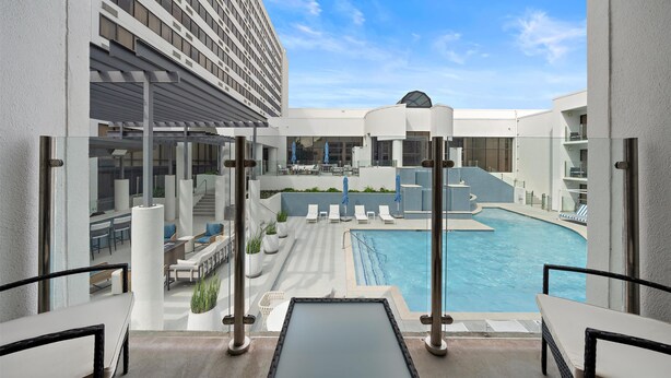 A modern hotel with a rooftop pool, outdoor seating, and a clear view of the sky. - Hilton College Station & Conference Center (College Station)