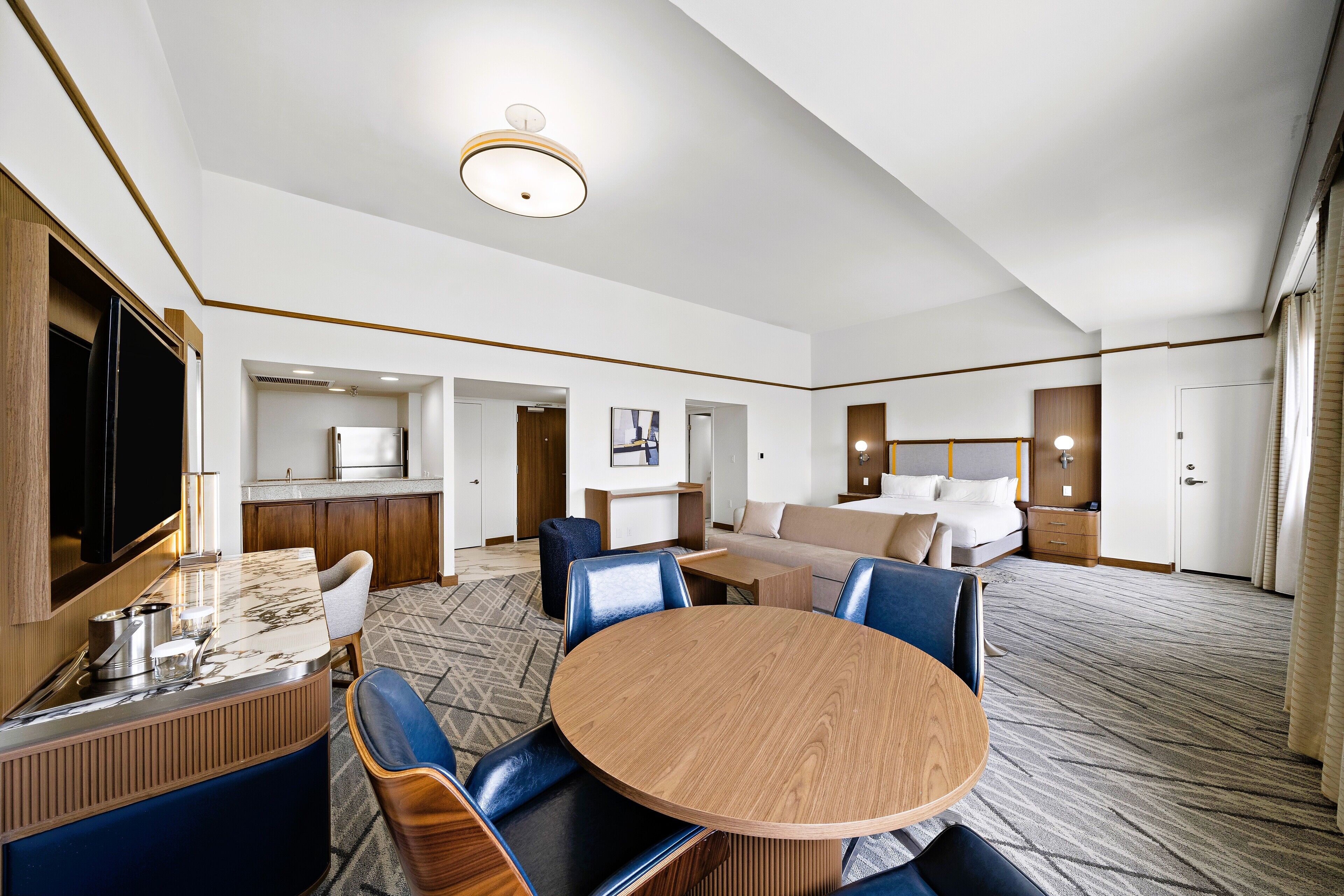 A hotel room with a dining area, a kitchen, a living area, and a bedroom.
