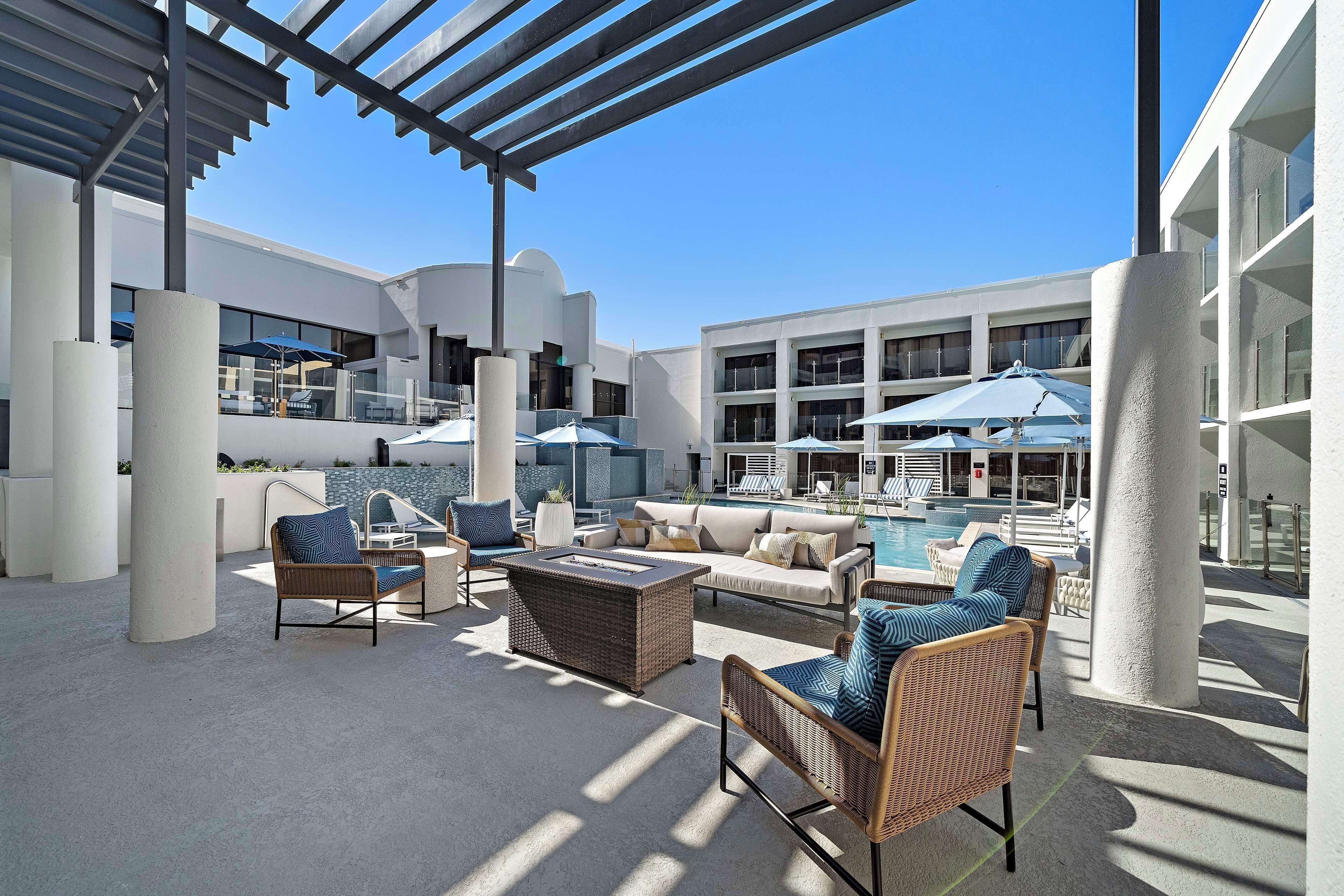 Un espace de détente extérieur moderne, avec des meubles en osier, une piscine et des parasols.