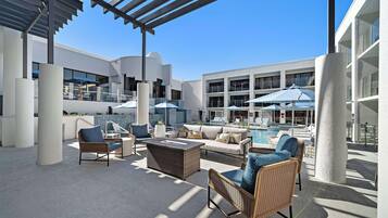 Un espace de détente extérieur moderne, avec des meubles en osier, une piscine et des parasols.