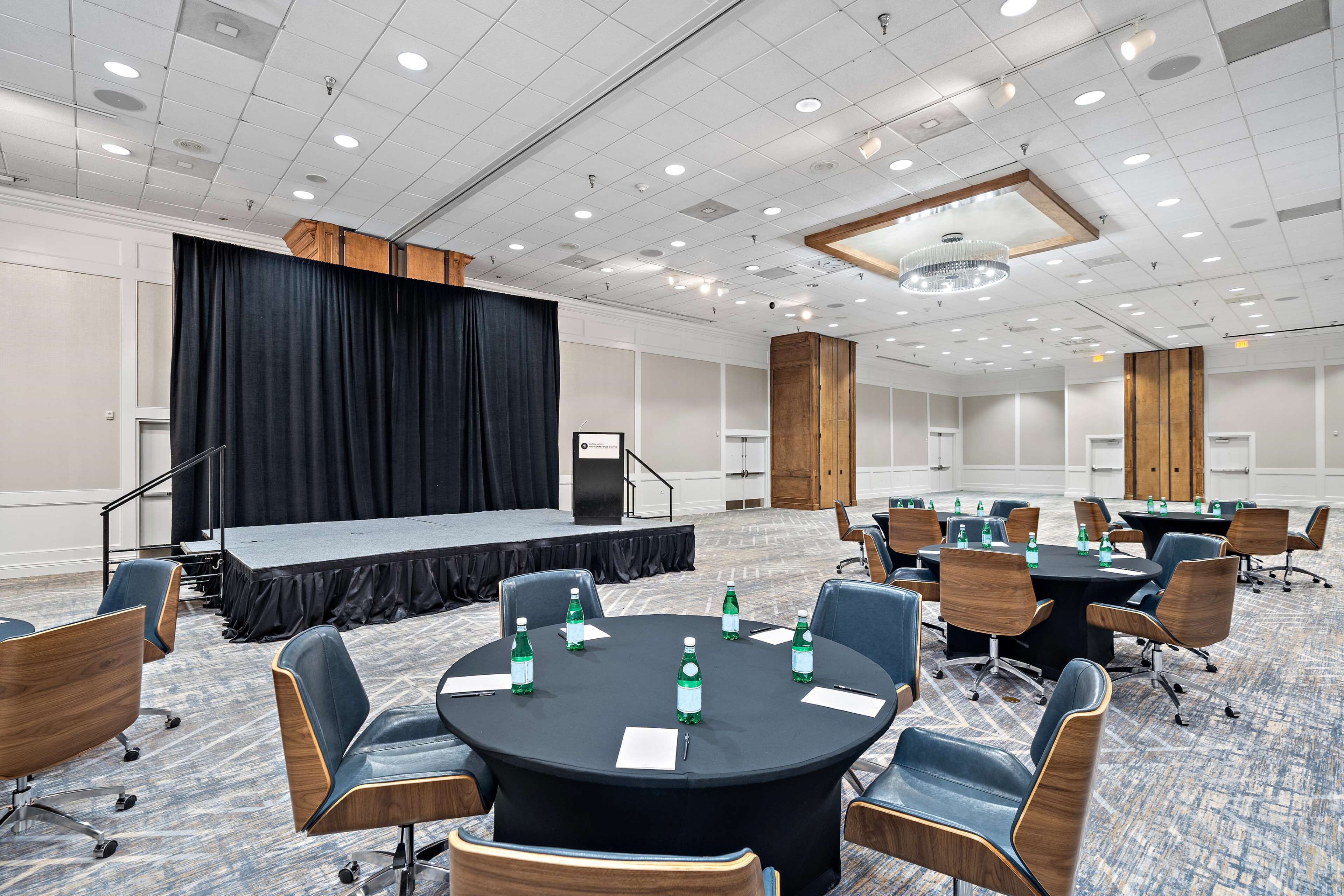 A conference room with a stage, round tables, and chairs.