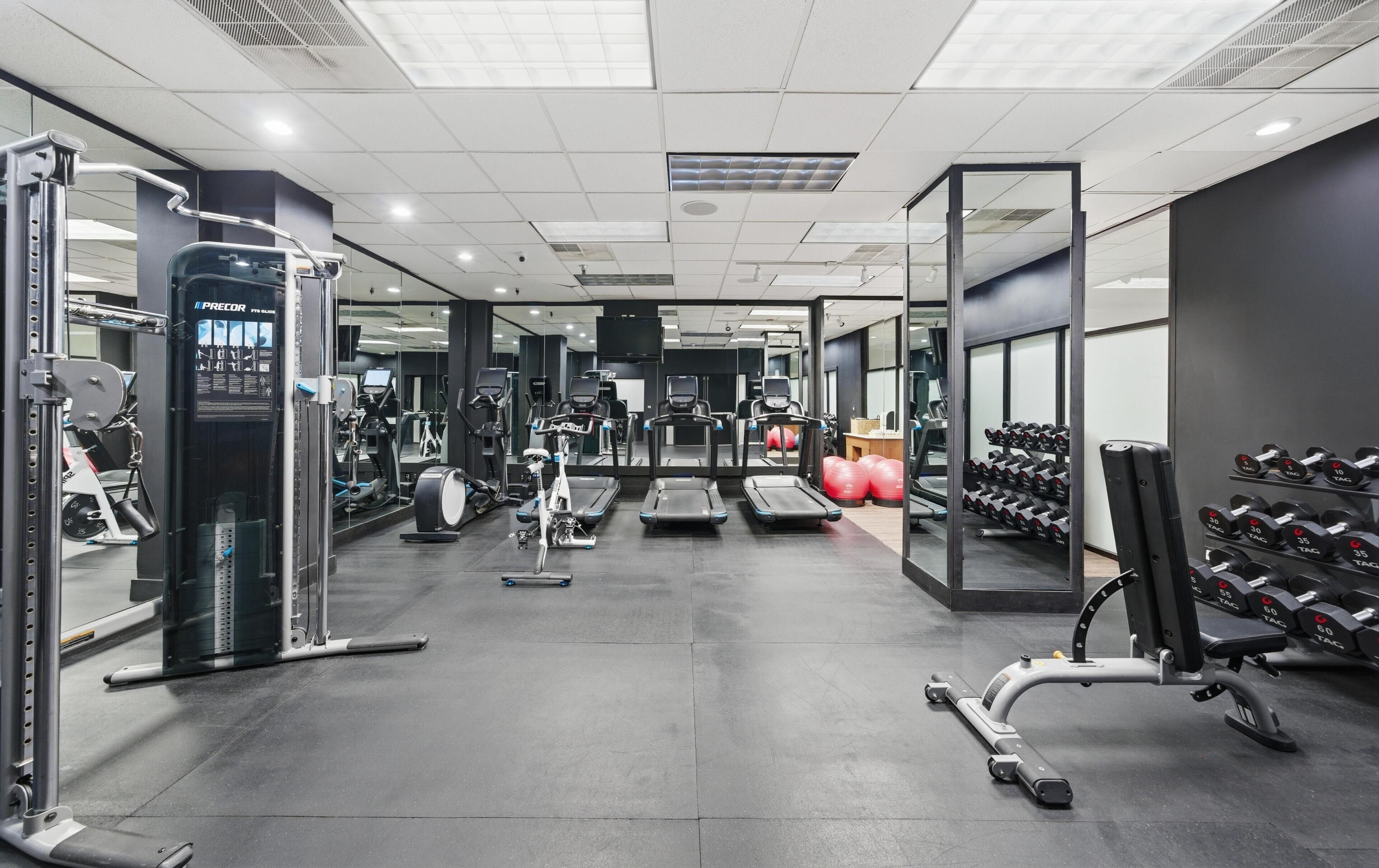 A modern gym with various exercise equipment, including treadmills, weight machines, and dumbbells.