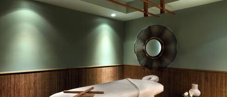 A room with a bed, wooden paneling, a round mirror, and a small table with candles.