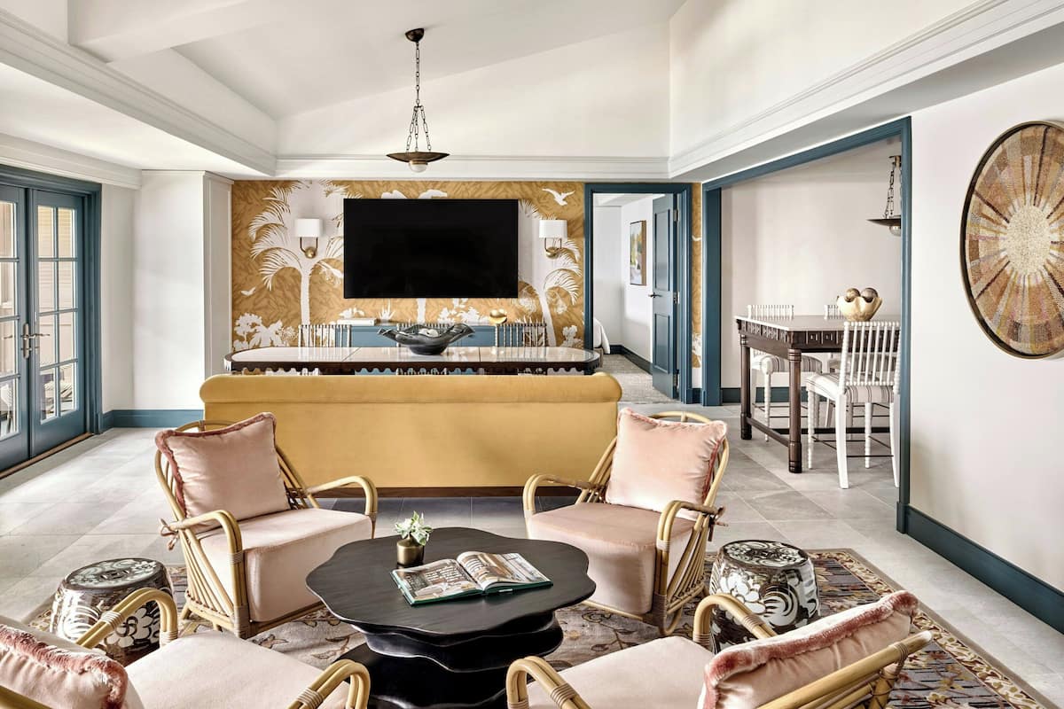 A spacious living room with a large sofa, two armchairs, a coffee table, and a dining area with a table and chairs.