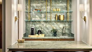 A kitchen with marble countertops, gold fixtures, and glass shelves.